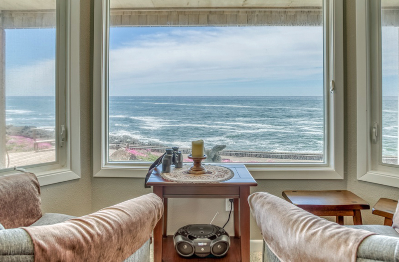 Oceanfront living room views from 2 comfortable chairs, binoculars, and a candle.