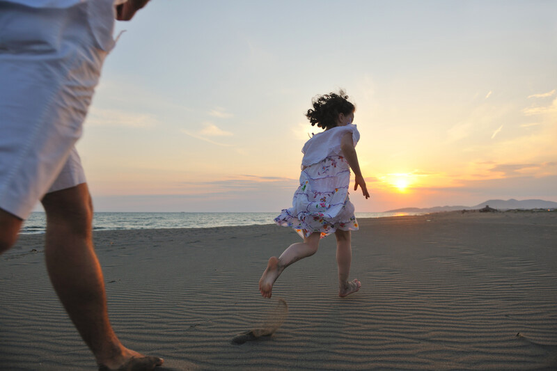 Child having fun running on the beach at sunset.