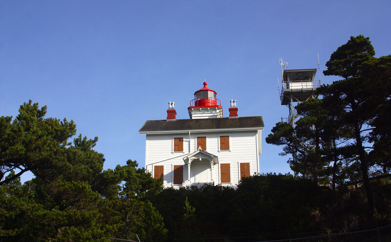 Square shaped lighthouse with red light on the top and boarded up windows.