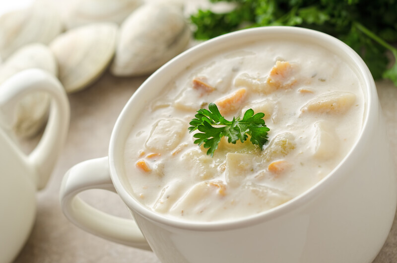 A big white soup cup filled with creamy clam chowder.