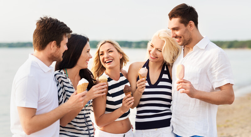 Friends on the beach enjoying ice cream cones.