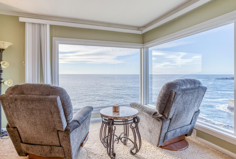 Two recliners with oceanfront views from floor to ceiling windows.